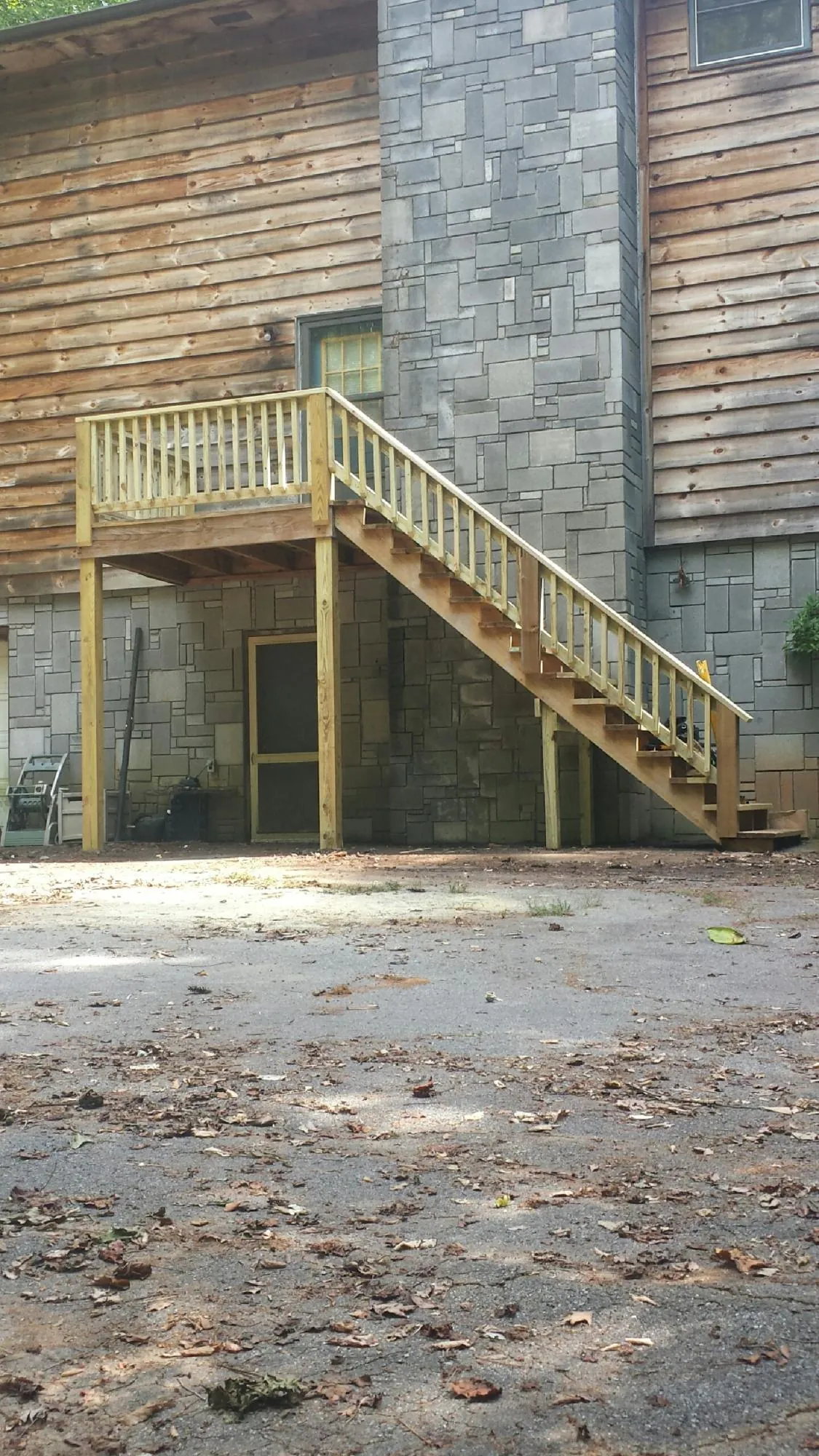 New pressure treated deck and stair landing on a log home in Collins